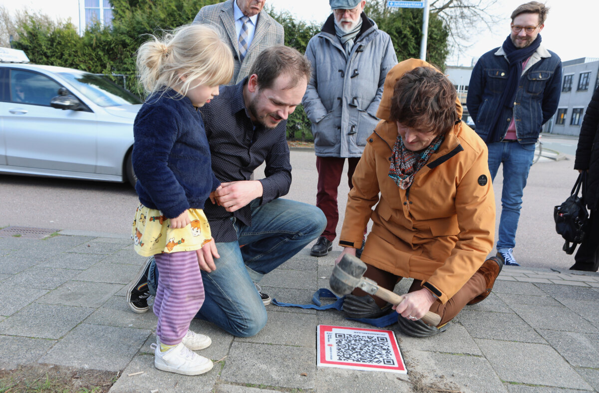 Julianaparklaan-bewoner Gonny Stoel legt de stoeptegel onder toezicht van Rick Companje van Het Utrechts Archief. Foto: Ton van den Berg