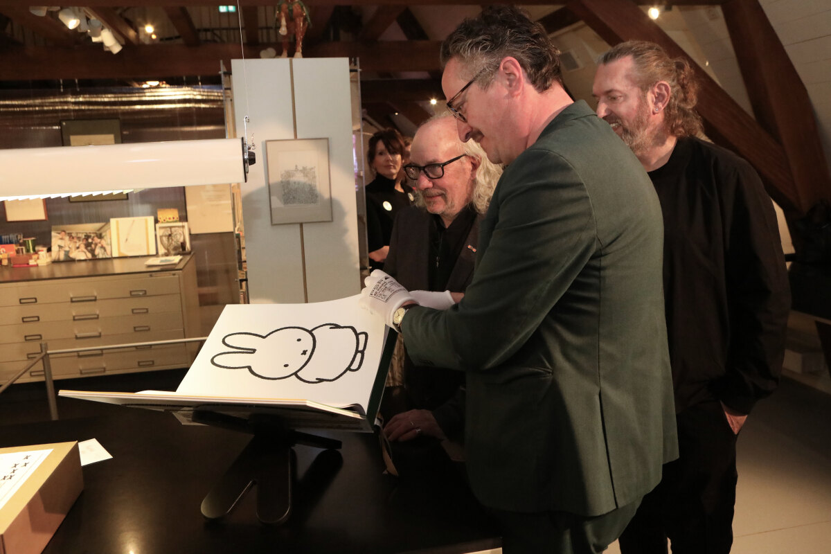 Bart Rutten (Centraal Museum) slaat een pagina om in het nieuwe nijntjeboek. Steven Hond (uitgeverij Komma) en Bob van Dijk (vormgever) kijken toe. Foto: Ton van den Berg