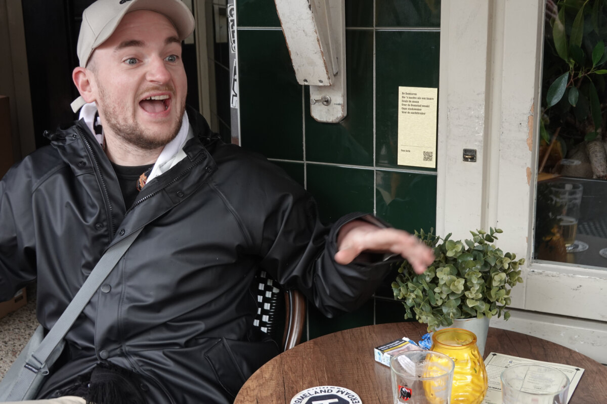 Tom Strik bij café De Voortuin aan de Neude, met achter hem zijn tekst. Foto: Ton van den Berg
