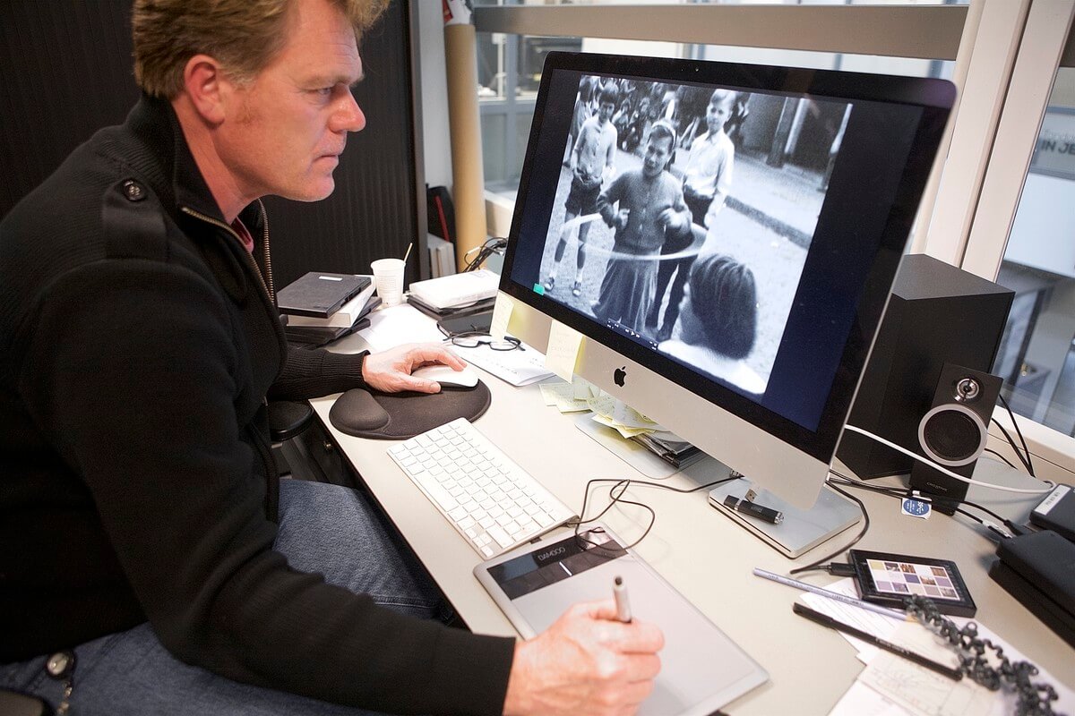 Lloyd Davies bij het bewerken van een gedigitaliseerde film van het buurtfeest in de Hoogstraat jaren vijftig. Foto: Ton van den Berg