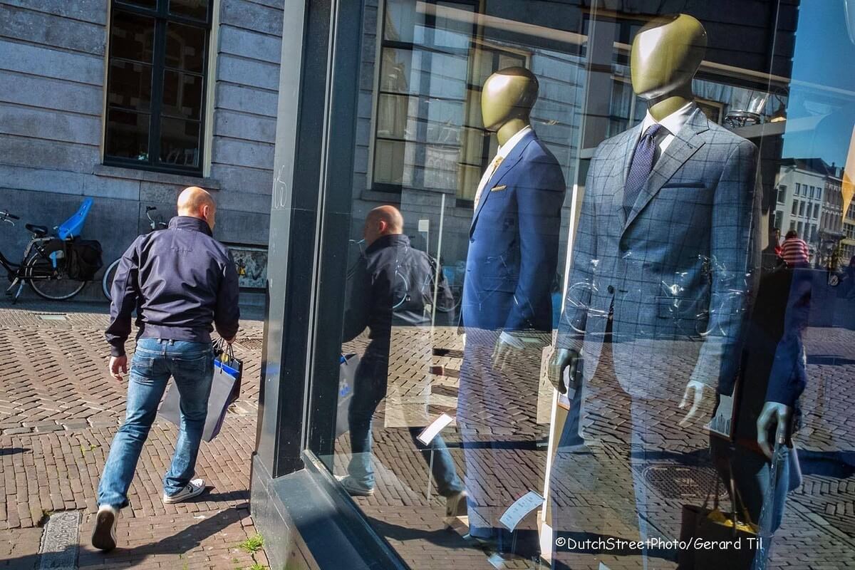 Een voorbijganger en een spiegelende etalage. Foto Gerard Til