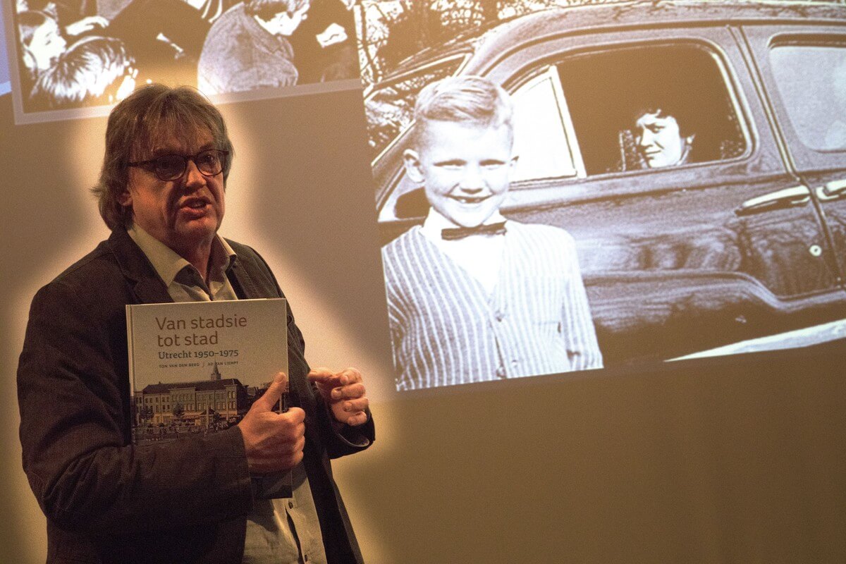 Henk Westbroek bij de foto van hemzelf die staat in 'Van stadsie tot stad'. Foto: B. Geerligs