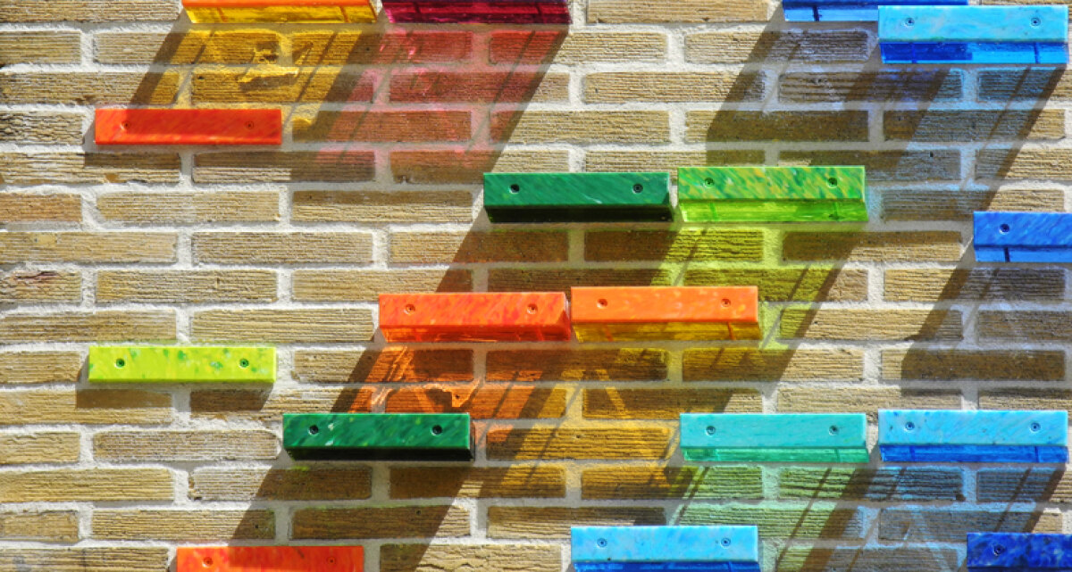 Het zonlicht valt in vele kleuren door de kunststof blokjes op de muur.