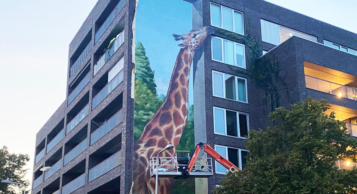 De giraf eet van een geschilderde geveltuin. Foto: JT
