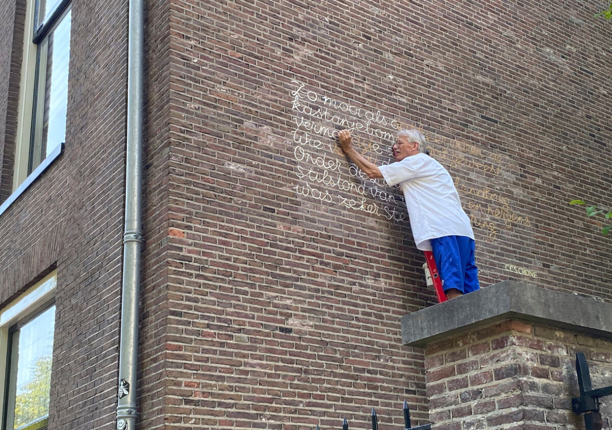 Jos Peeters restaureert het gedicht van C.C.S Crone op de zijgevel Miquelhuis (2023). Foto: Jim Terlingen/HUA