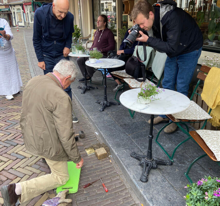 André Janning (83) legt de struikelsteen voor zijn oom Louis Trompetter. Zijn zoon Edward kijkt toe. Foto: Jim Terlingen