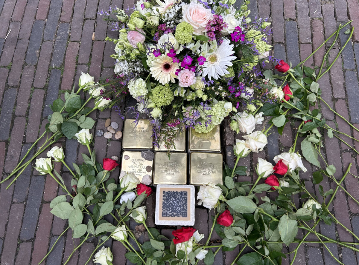 Na afloop: de zes geplaatste steentjes en de steen met QR-code met de erbij gelegde bloemen (foto: JT)
