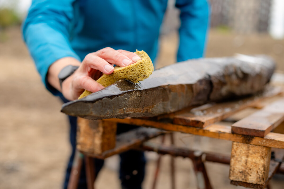 Vrijwilligers maken het Romeinse hout voorzichtig wschoon met een spons waardoor de bewerkingssporen tot in detail bewaard zijn gebleven. Foto Abe Jonker