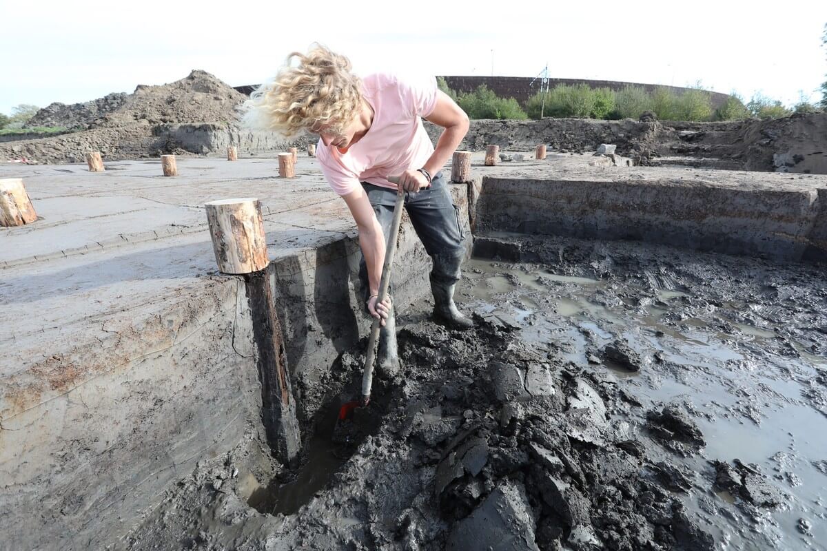 Een archeoloog graaft een van de 16 palen uit die behoren bij de resten van een Romeinse brug. Foto: Ton van den Berg