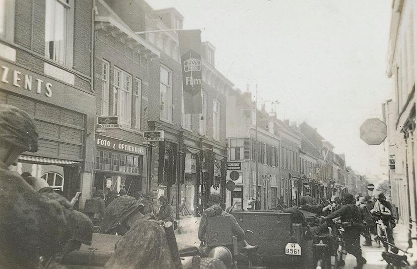 Duitse soldaten staan links aan de overkant bij een fotozaak op jacht naar fotorolletjes. De foto komt uit een fototoestel van een bij de slag overleden SS'er. oto: Collectie Martin Brink, Veenendaal