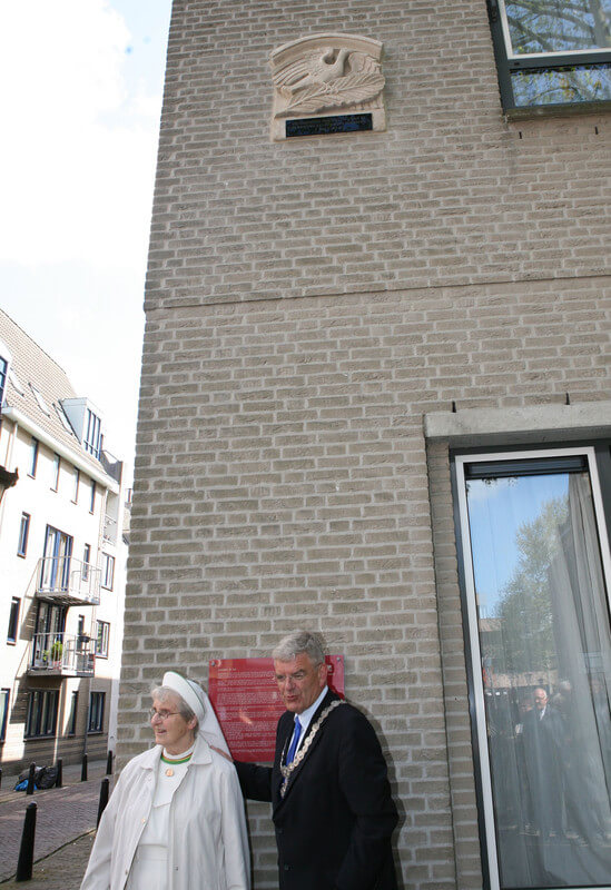 Zuster Van Dijk en burgemeester Van Zanen onder de gevelsteen De Duif. Foto: Ton van den Berg