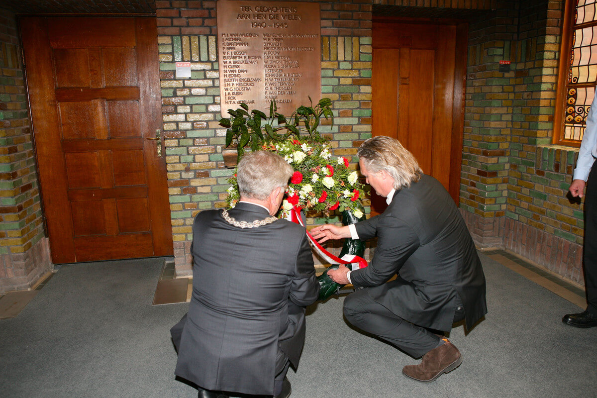 Van Zanen en Eringa leggen een krans bij de lijst met namen van Utrechtse spoorwegmensen die omkwamen in de oorlog. Foto: Ton van den Berg