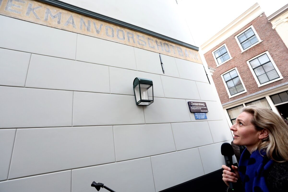 Wethouder Klein bij de onthulling van de ontdekte muurreclame. Foto: Ton van den Berg