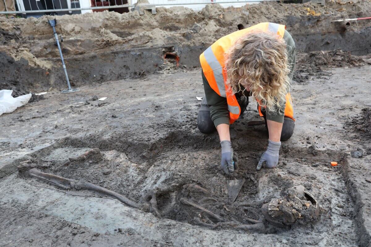 Archeoloog Gerben Beeuwkes verwijdert modder rond het gevonden skelet 'Renee'. Foto: Ton van den Berg