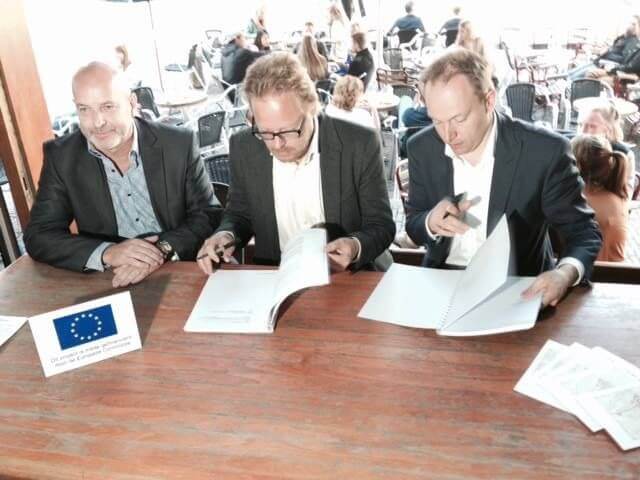 Wethouder Kreijkamp (rechts) ondertekent een overeenkomst met City Wireless die het gratis netwerk aanlegt en beheert. Foto: Twitter/cafe De Zaak