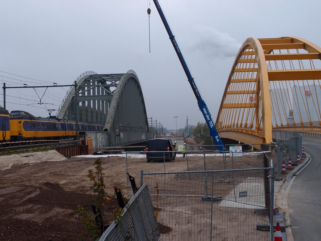 De nieuwe spoorbrug komt tussen de twee bestaande bruggen te liggen.