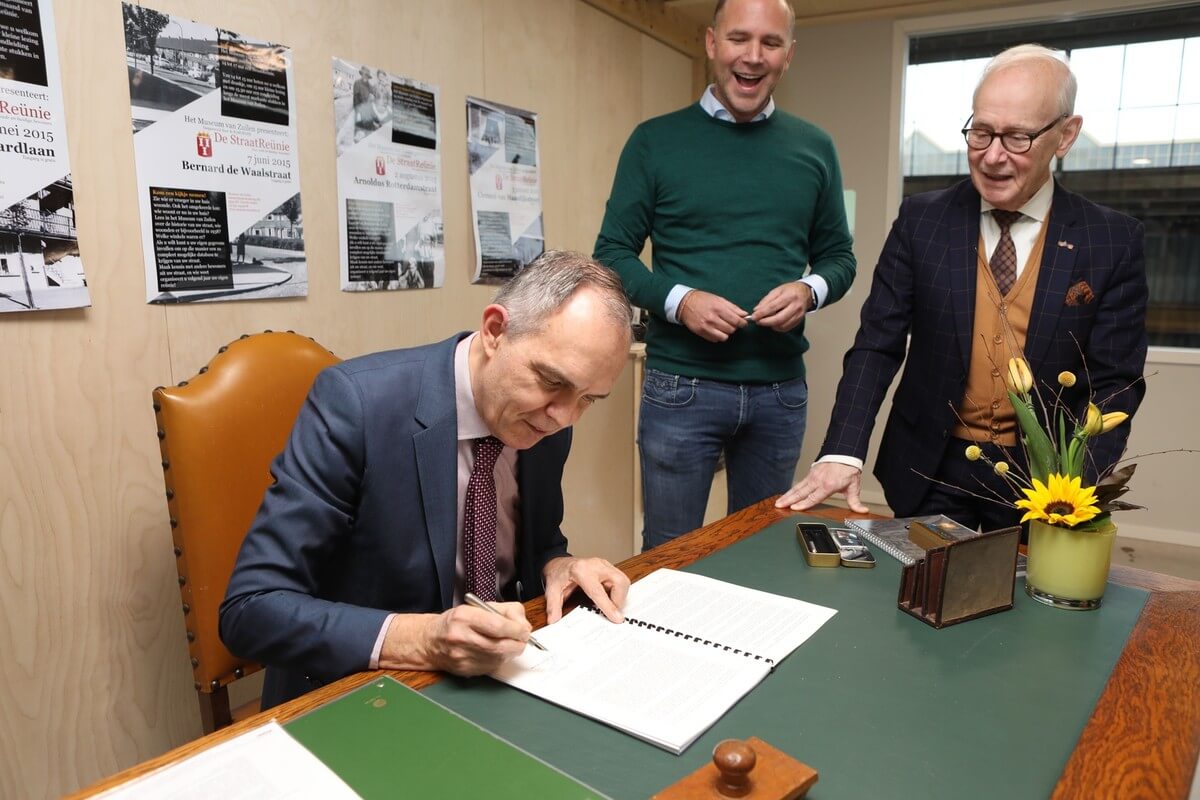 Paulus Jansen zet zijn handtekening, Bob Scherrenberg (midden) en Wim van Scharenburg kijken toe. Foto: Ton van den Berg