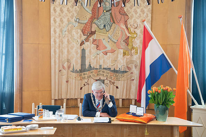 Burgemeester Van Zanen belt met de lintjesdragers. Foto: Robert Oosterbroek