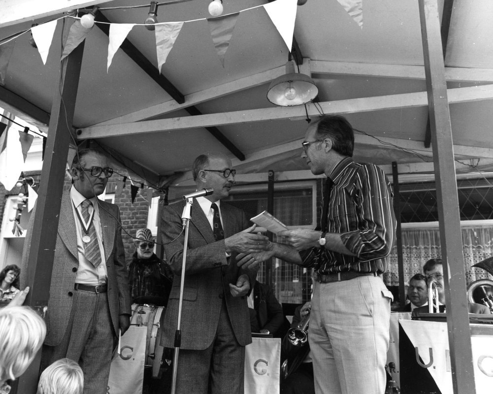 In 1978 overhandigt Gerrit Jansen zijn boek over de Kovelaarstraat aan wethouder Cees Pot. Voorzitter van de buurtvereniging Kovelaarstraat B. van der Tier, kijkt toe. Foto: HUA