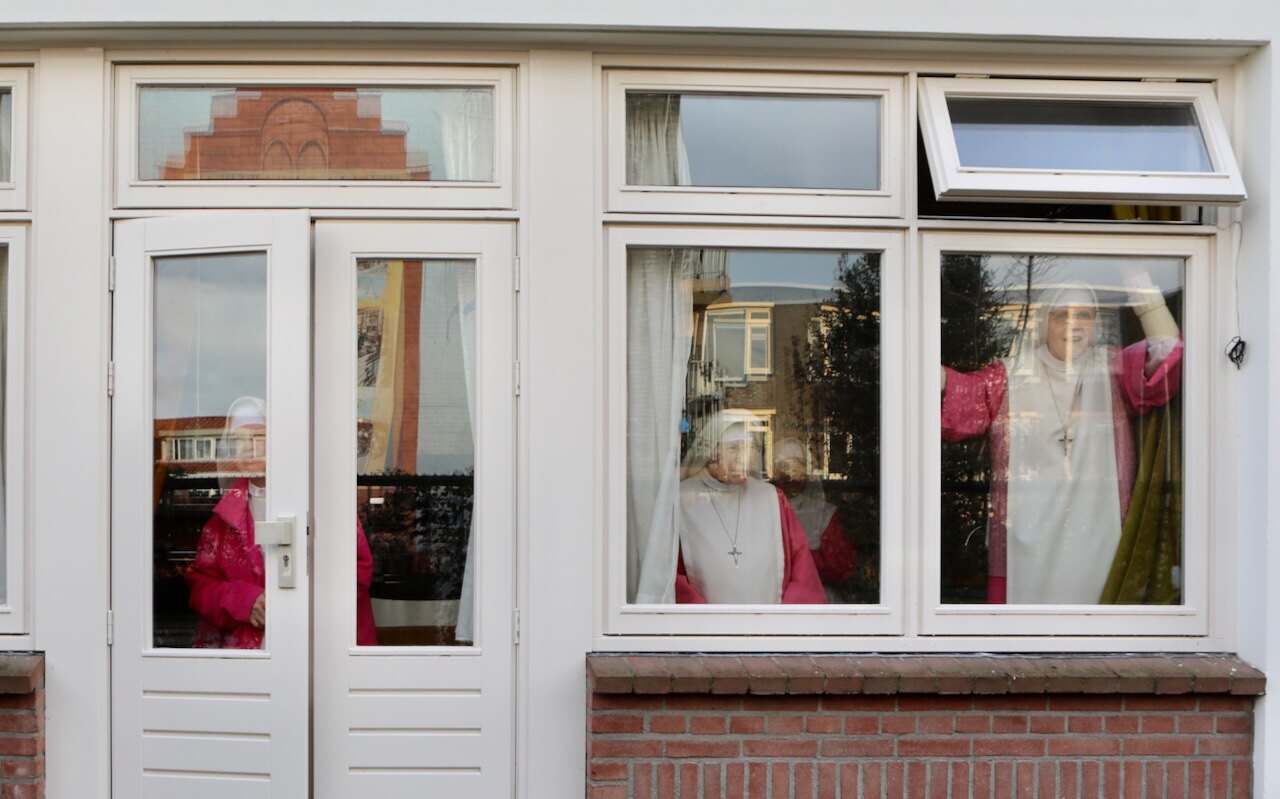 Zusters van het klooster Cenakel volgen de 'inwijding' van de muurschildering vanachter glas. Foto: Ton van den Berg