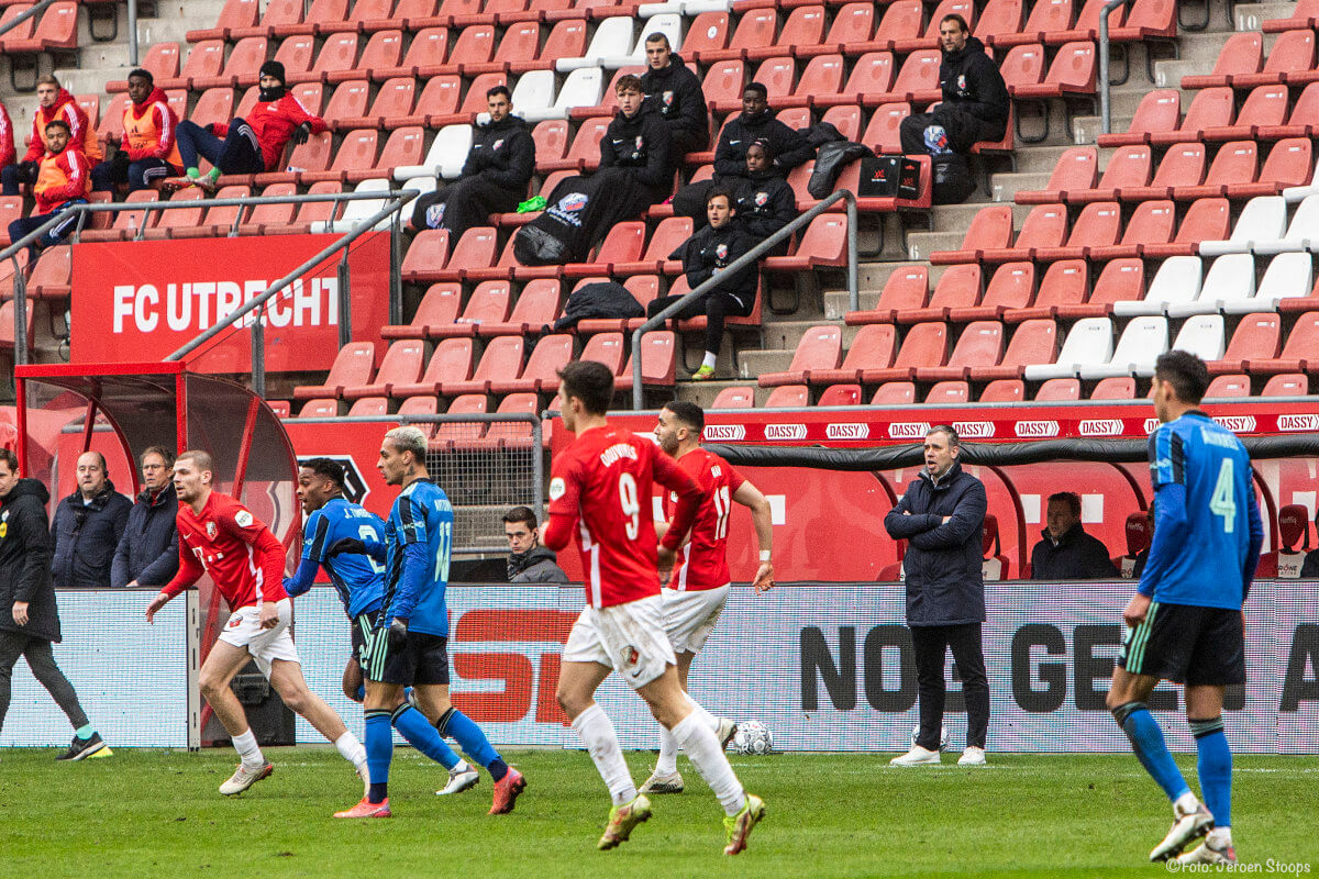 Trainer Hake en de spelers op de bank van FC Utrecht (die in verband met de Coronamaatregelen op de tribune zitten) kijken toe.