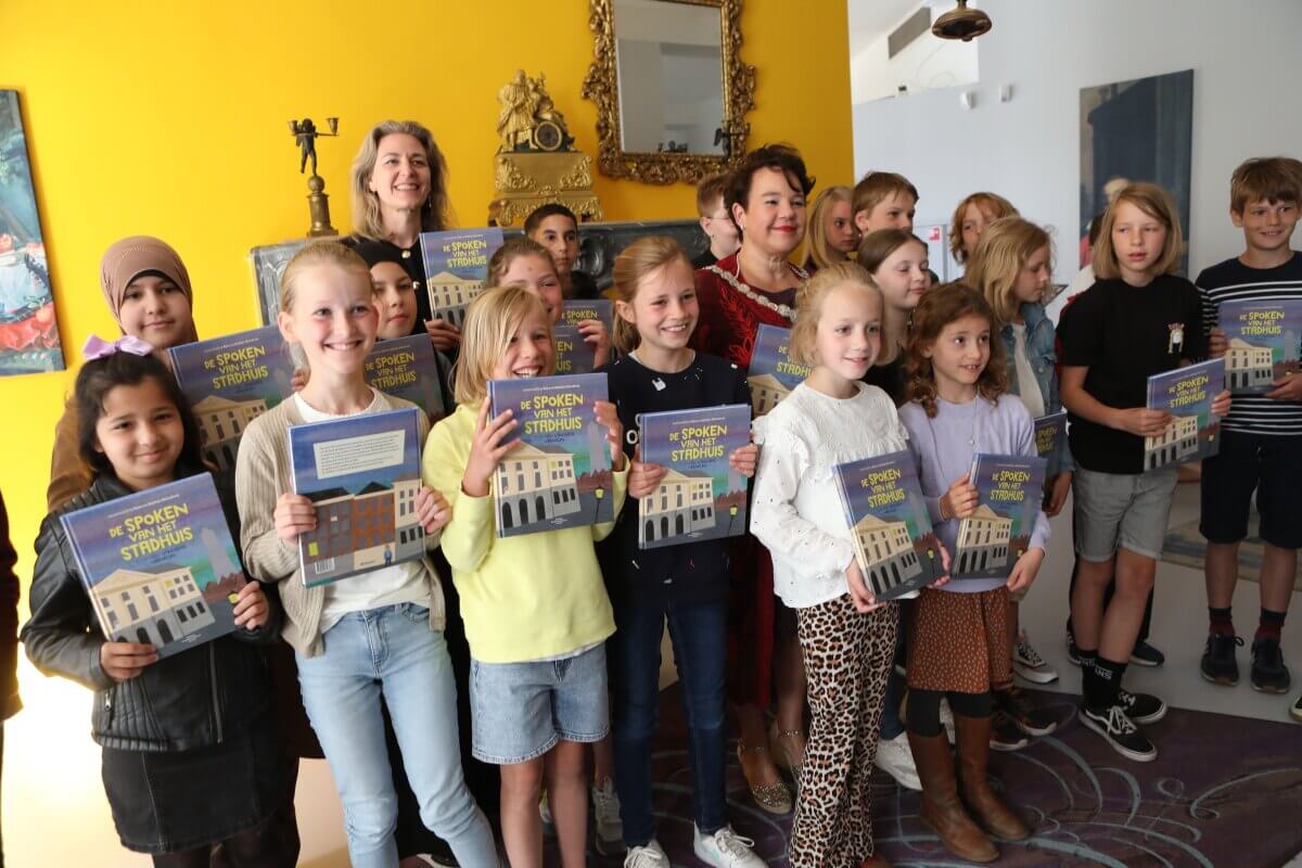 Schoolkinderen krijgen het boek 'Spoken van het Stadhuis'. Foto: Ton van den Berg
