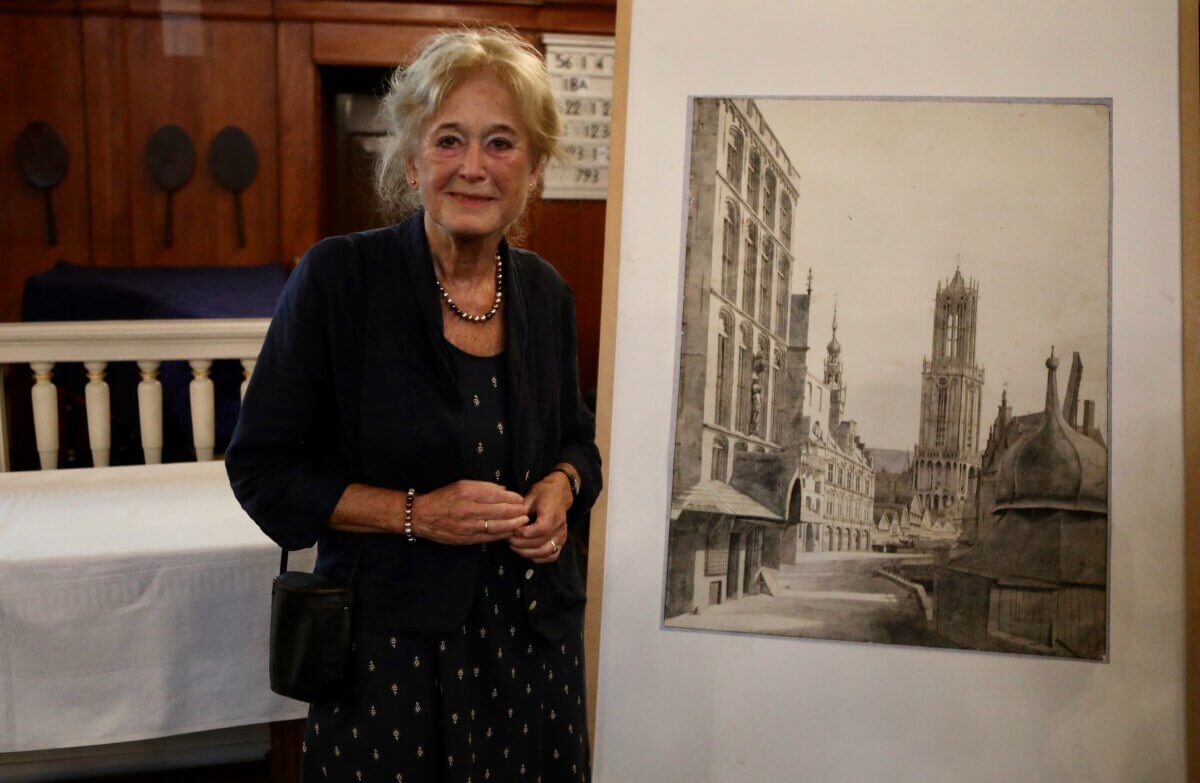 Tolien Wilmer bij de (uitvergrote) tekening van Saenredam met zicht op de Stadhuisbrug en Domtoren in de 17e eeuw. Foto: Ton van den Berg