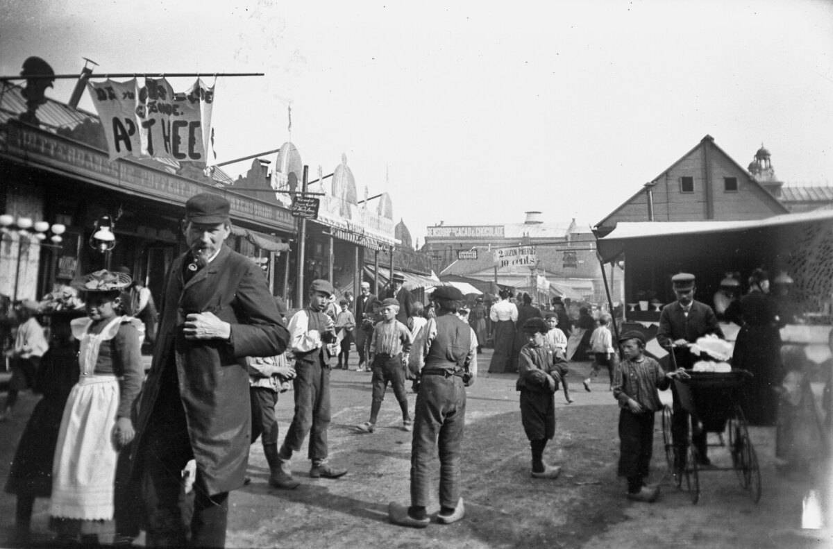 Een prachtige foto van de zogenoemde 'Lepelstraat'. De foto is genomen vanaf ongeveer de zuidoosthoek van “De Liggende Os”. De Lepelstraat liep vanaf de zijkant van het hotel midden over de kermis naar de Schouwburg, welke we in de verte zien.