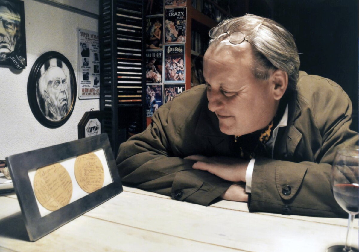 Jan Fokkens (initiatiefnemer Tourlobby) in café De Winkel van Sinkel met de ingelijste bierviltjes uit 2002. Foto: JW (2013)