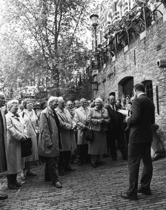 Oplevering van de werfmuren in 1985 met vooraan wethouder Van Willigenburg en in het midden (met tasje) burgemeester Vos-Van Gortel en rechts naast haar restaurateur H.J. Jurriëns. Ir. Dam staat bij de werfdeur. Foto: GAU