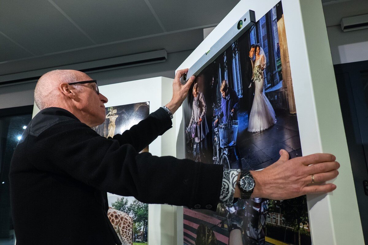 Fotograaf Gerard Til hangt een foto recht in de expositie. Foto: Michiel Wijnbergh