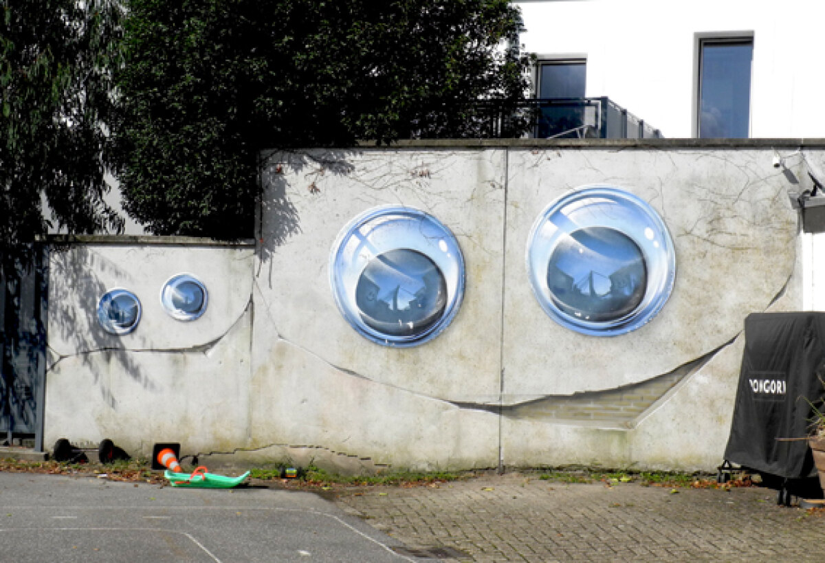 Aan de Elgarlaan zijn twee gezichtjes van JanIsDeMan te zien met de karakteristieke scheve mond. De bakstenen en de barsten heeft hij hier erop geschilderd. Foto: JvW
