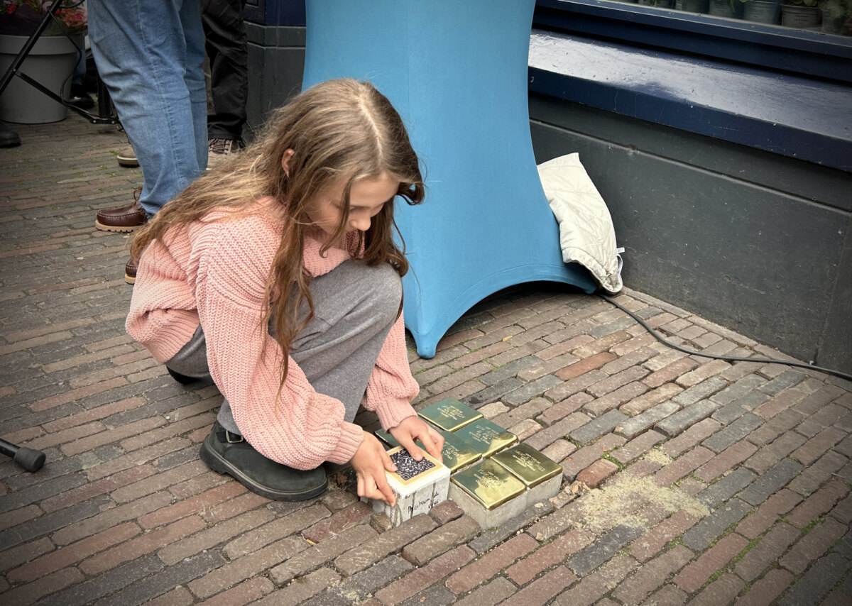 Hannah, een van de huidige bewoners, plaatst als laatste de steen met de QR-code (JT)