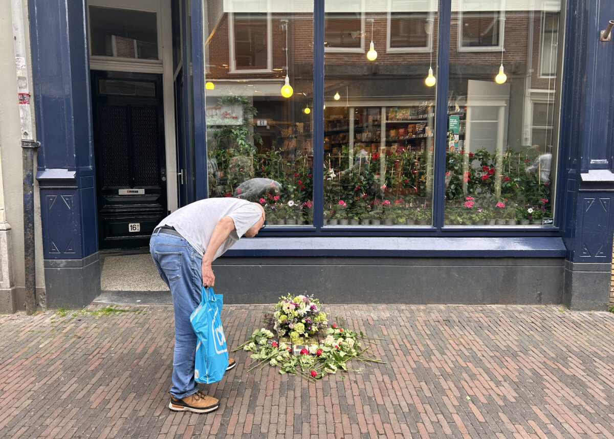 Na afloop van de plechtigheid leest een supermarktbezoeker de namen op de steentjes. Foto: JT
