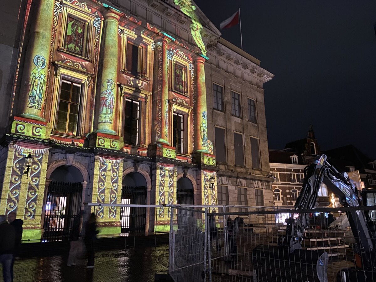 De lichtprojectie op het Stadhuis met rechts hekken.