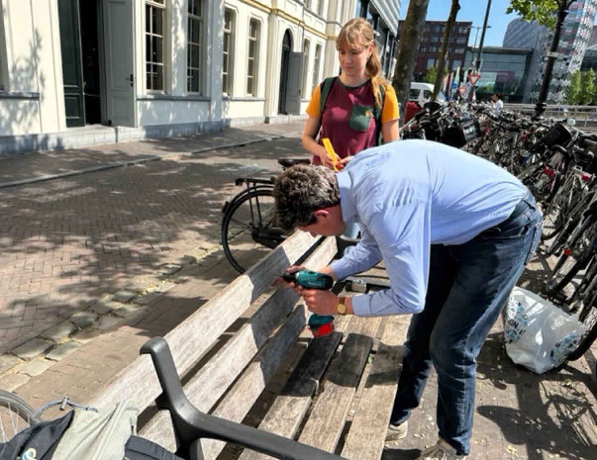 Martijn Bac en Jacqueline van Eck bezig met het omdopen van het bankje op de Catharijnekade. Foto: DB