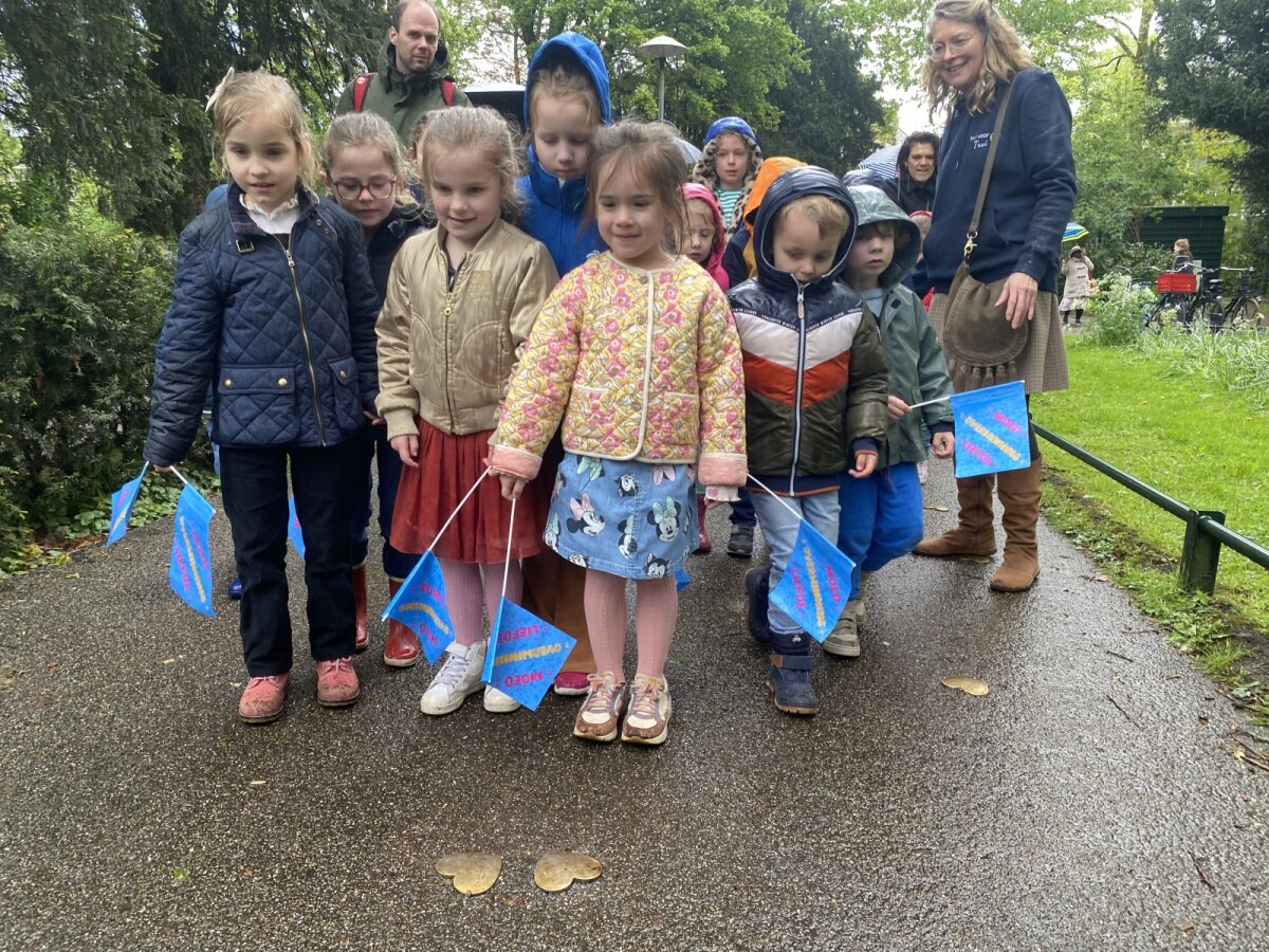 Kinderen staan stil bij twee hartjes die naast elkaar geplaatst zijn. Zij symboliseren Deetje en Joekie, een joodse tweeling die het langst in Kindjeshaven heeft gezeten. Foto: JT