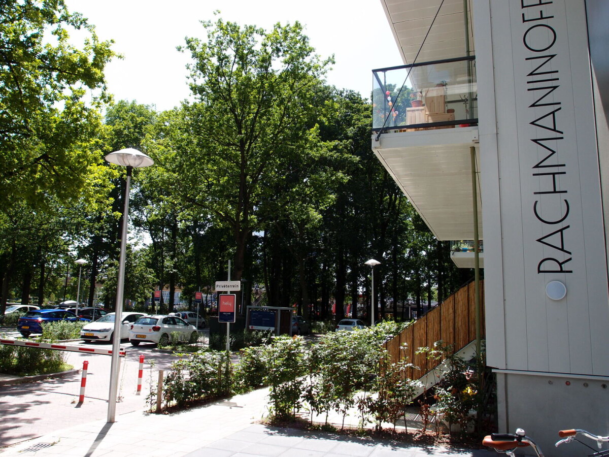 Een deel van het tot appartementencomplex ‘Rachmaninoff’ omgebouwde voormalige ROVU-pand met zicht op de parkeerplaats en het achterliggende Hommelbos (foto LE)