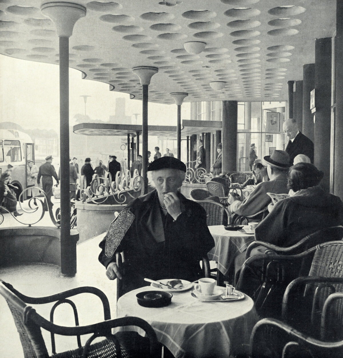 Het terras van het Centraal Station aan het Stationsplein met op de voorgrond Mietje Lijdsman-Smit, genietend van het chocoladeflikje in het taartje dat ze bestelde bij de stationsrestauratie (foto G.J. Lauwers, Het Utrechts Archief).