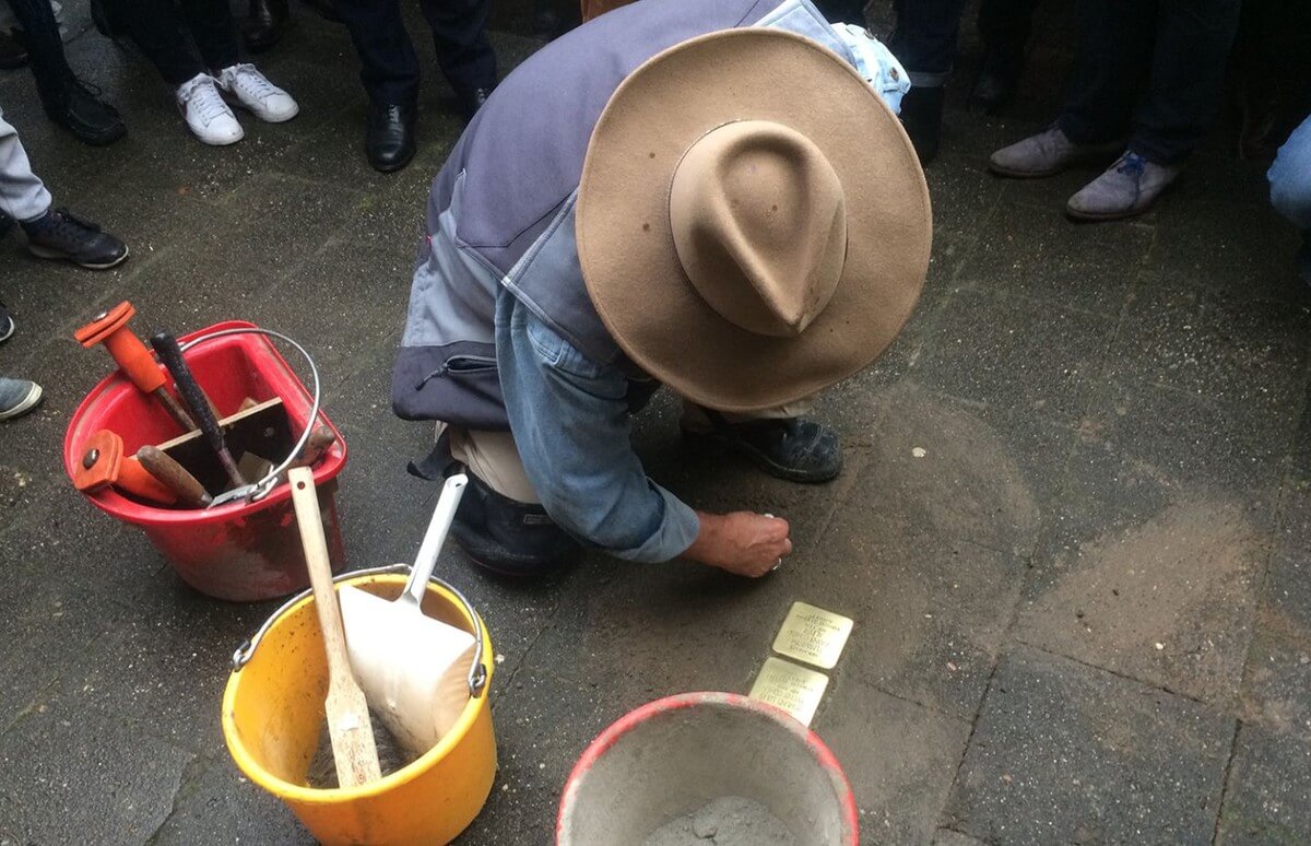 Een ontroerend gebaar: Gunter Demnig veegt op Mauritsstraat 93 na zijn werk de steentjes schoon. Foto: Jim Terlingen