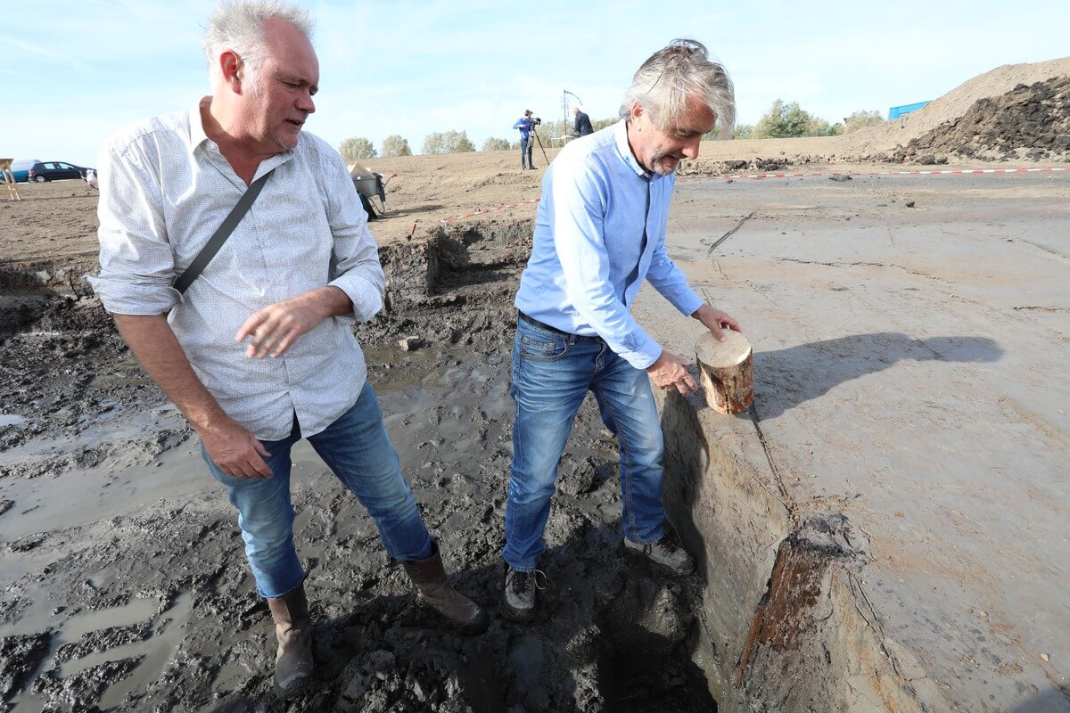 Archeologen Herre Wynia en Erik Graafstal bestuderen de eiken palen. Foto: Ton van den Berg