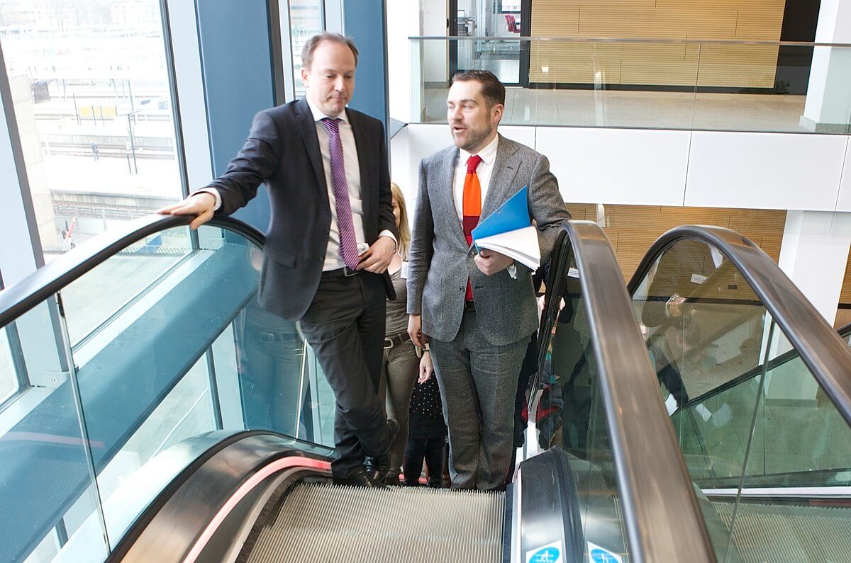 Wethouder Kreijkamp en staatssecretaris Dijkhof op de roltrap in het Stadskantoor. Foto: Ton van den Berg