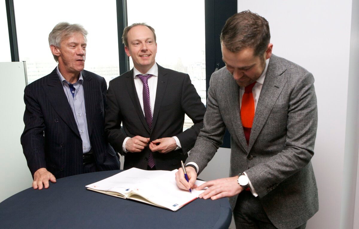 Staatssecretaris Dijkhof zet zijn handtekening onder de samenwerking in het Expat Center. Wethouder Kreijkamp glundert. Foto: Ton van den Berg