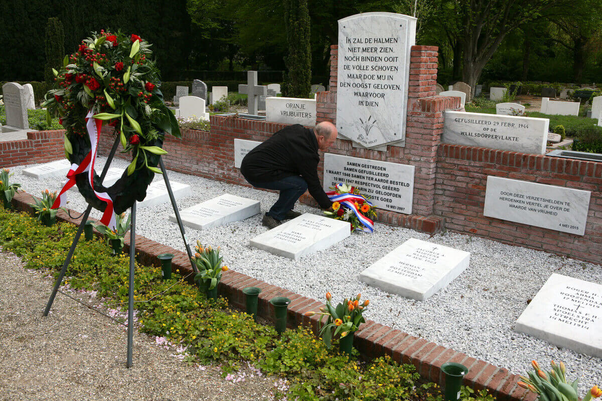 Een nabestaande legt bloemen bij het monument voor de Oranje Vrijbuiters. Foto: Ton van den Berg