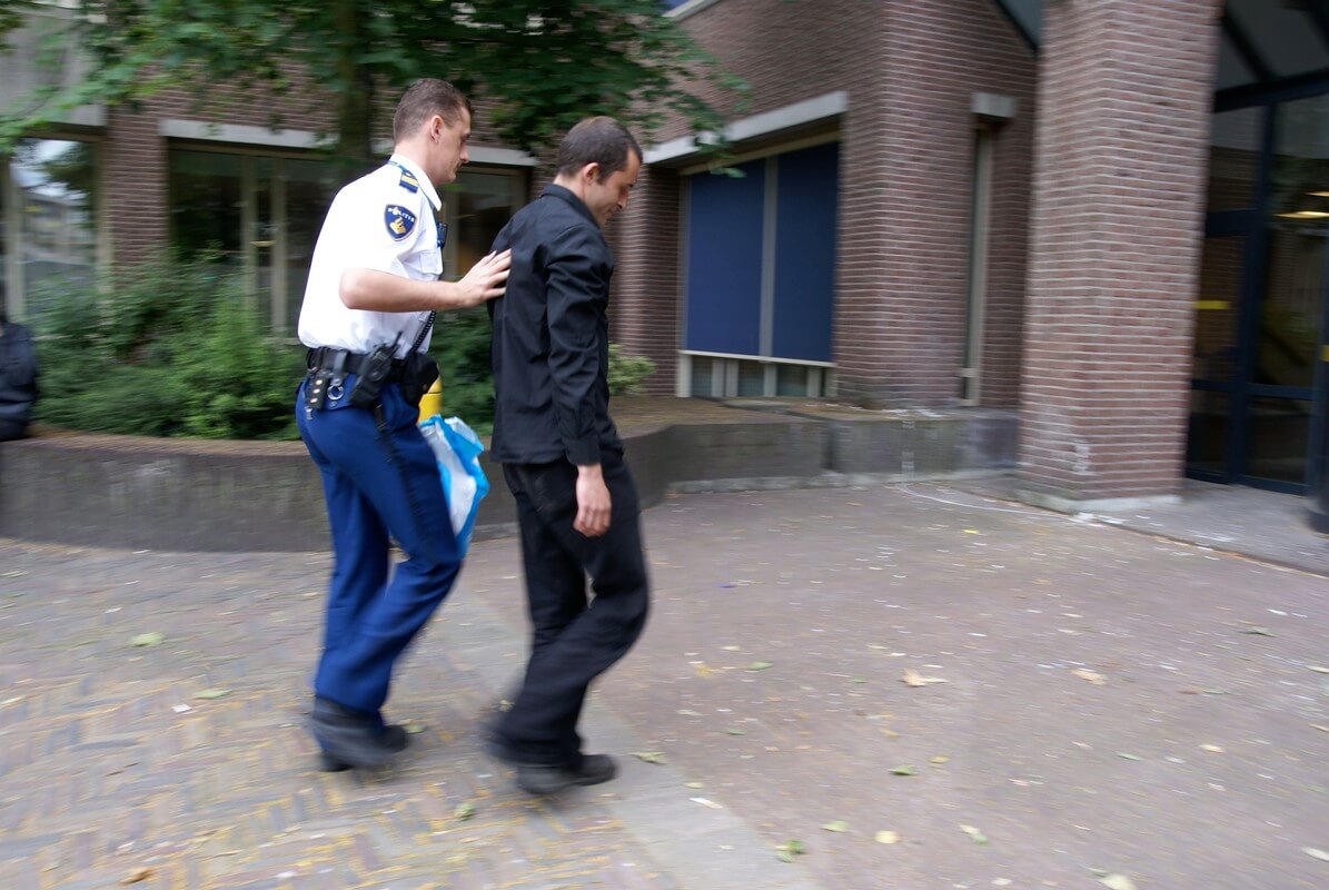 Meijerink wordt na zijn arrestatie naar binnen geleid. Foto: Ton van den Berg
