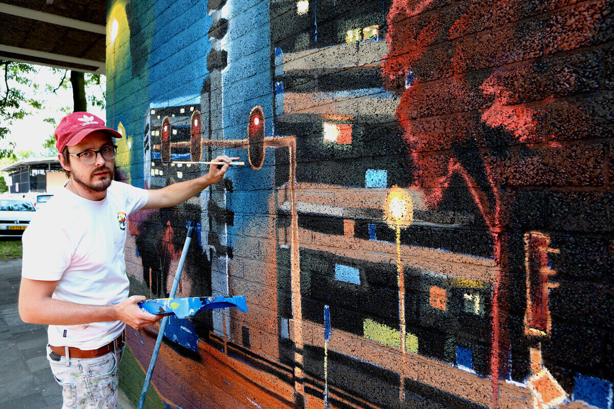 De Verfdokter aan het werk op een muur in het Tuindorp-West Complex. Foto: Ton van den Berg