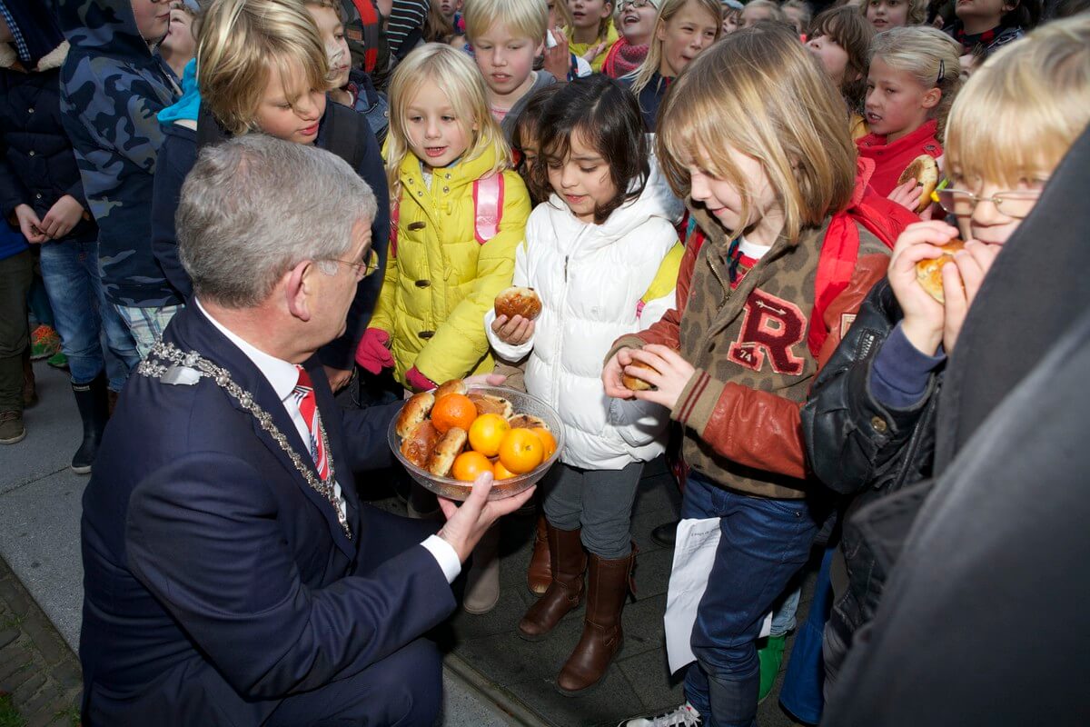 Burgemeester Van Zanen deelt krentenbollen en mandarijnen uit. Foto: Ton van den Berg