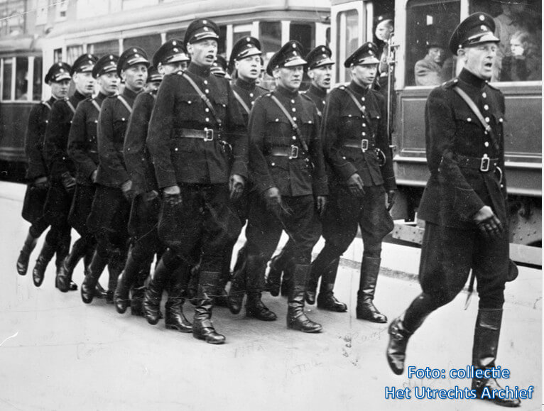 Een groep marcherende en zingende politieagenten (‘Schalkhaarders’) op het Stationsplein, 1942. Foto: Collectie Het Utrechts Archief