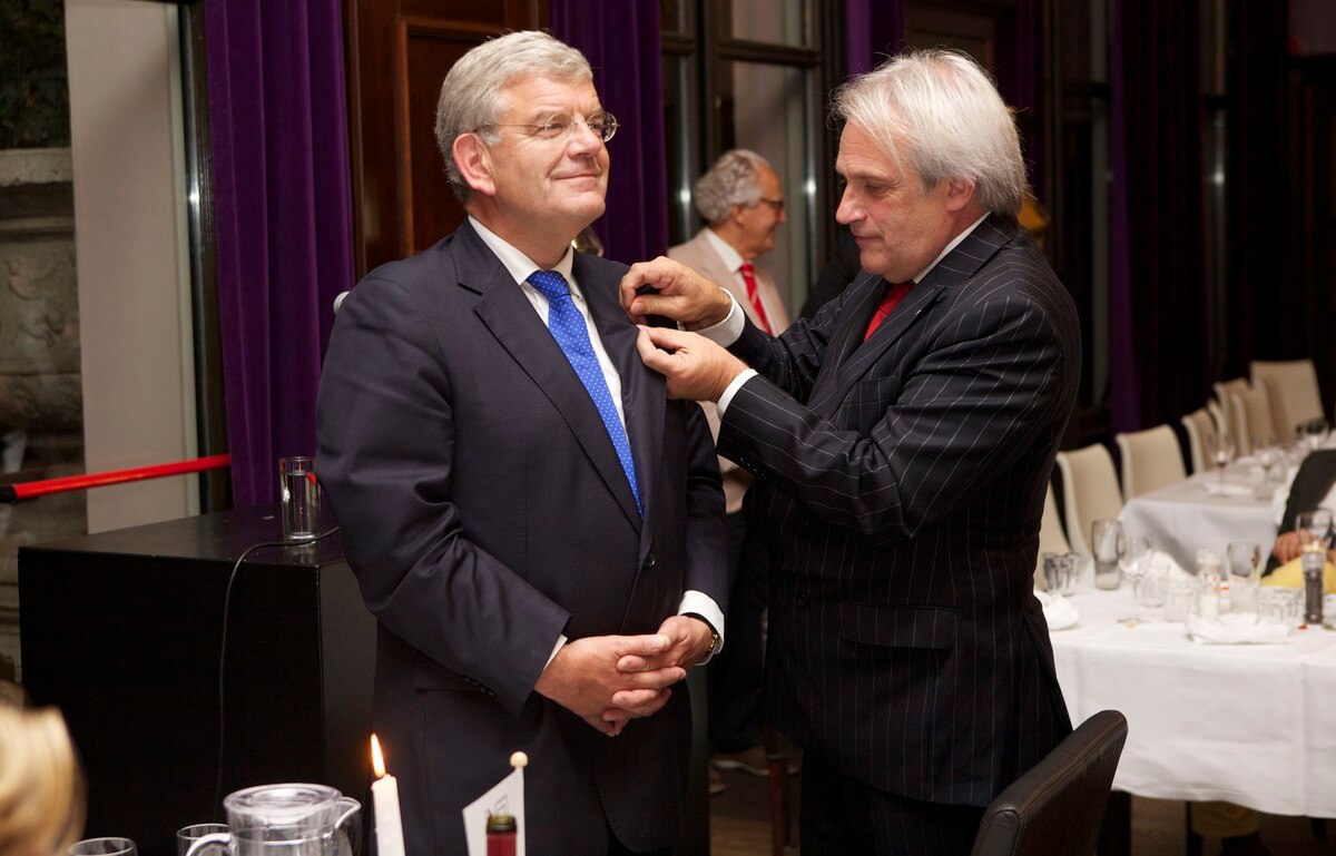 Sociëteit-voorzitter Jan van Dijkhuizen spelt een lidmaatschapsspeldje op jas van Van Zanen. Foto: Ton van den Berg