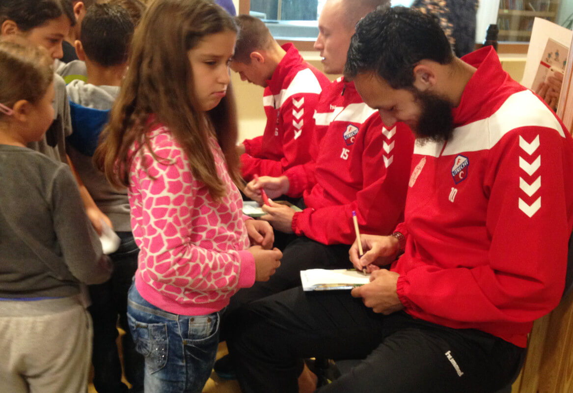 Spelers Filip Bednarek, Mark Diemers en Nacers Barazite van FC Utrecht worden belaagd door de kinderen van de Da Costaschool in Kanaleneiland. Foto: Zita Eijzenbach